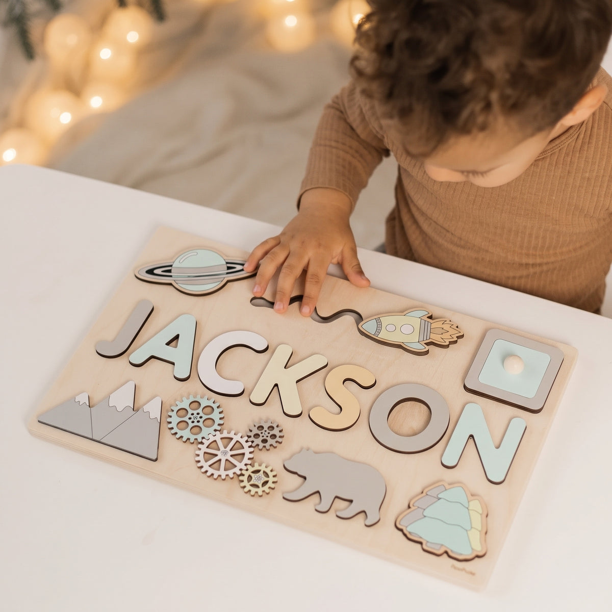 Boy placing the rocket piece into the Momi Toys Personalized Wooden Name Puzzle, Explorer design