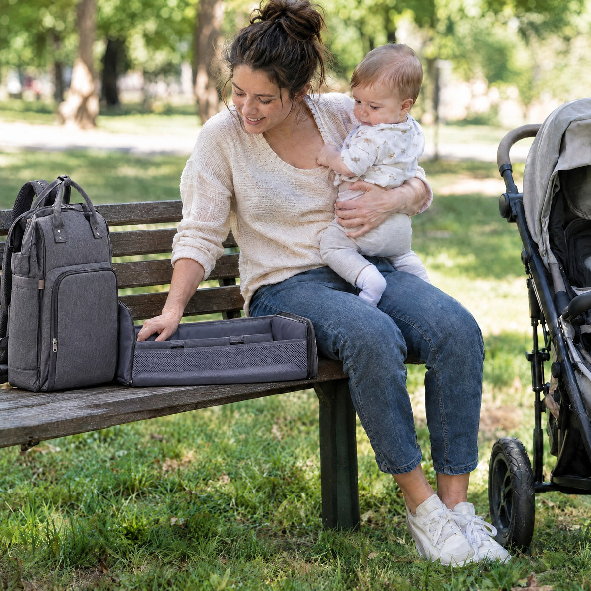 Momi Toys 3-in-1 diaper bag backpack unfolded into a changing station on a park bench