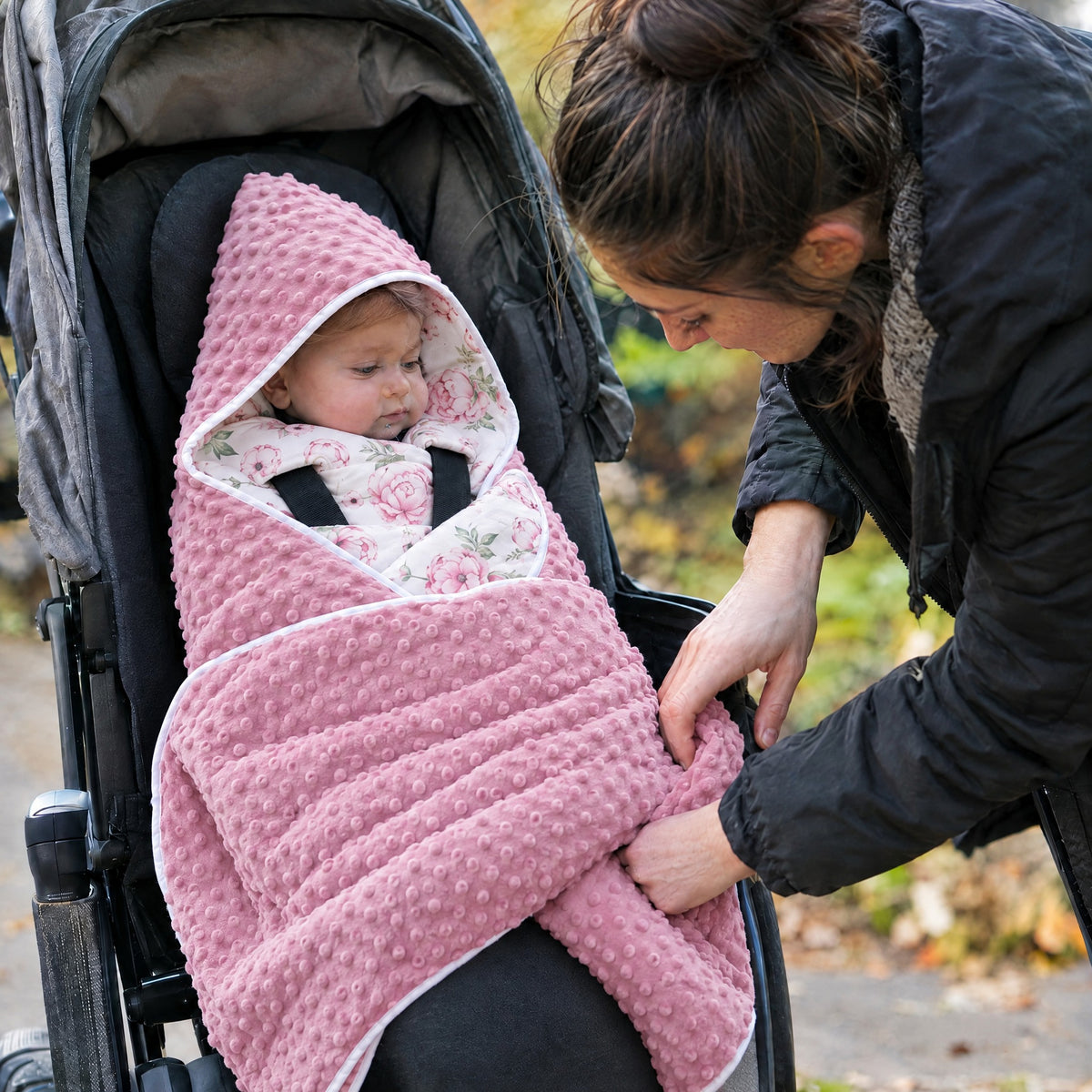 Baby in a stroller wrapped in the Momi Toys dusty rose floral minky swaddle blanket
