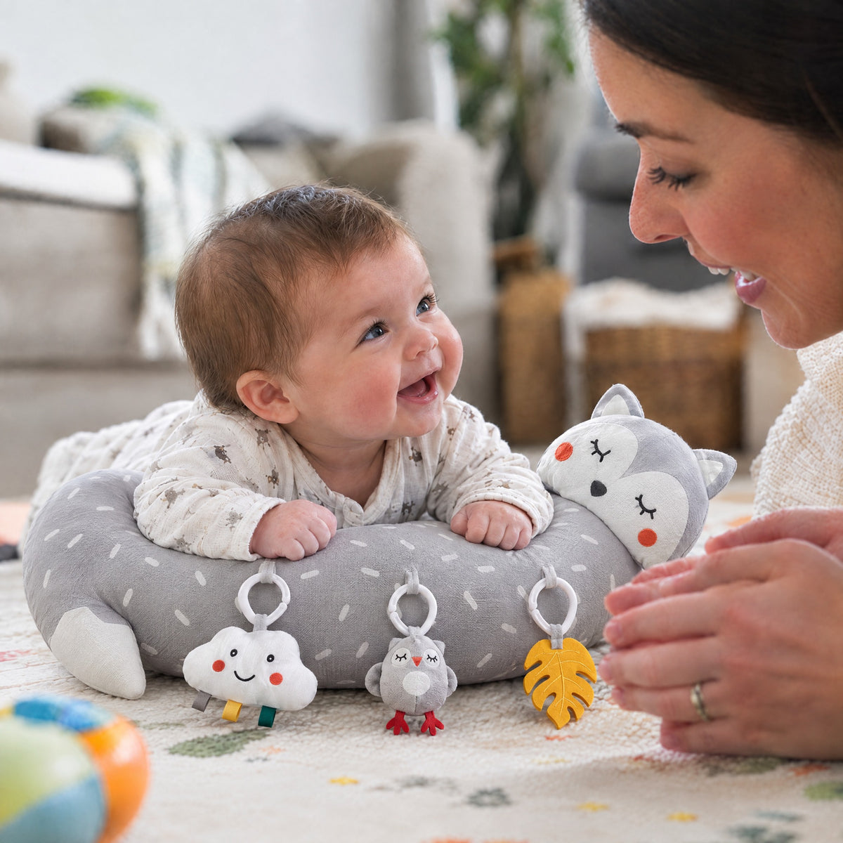 Baby doing tummy time on the Momi Toys grey fox tummy time pillow with hanging toys