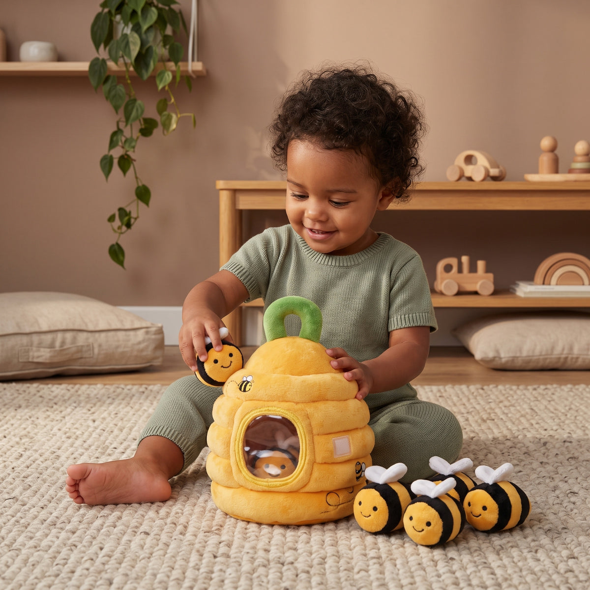 Toddler playing with Momi Toys plush beehive sensory toy, placing a plush bee into the hive